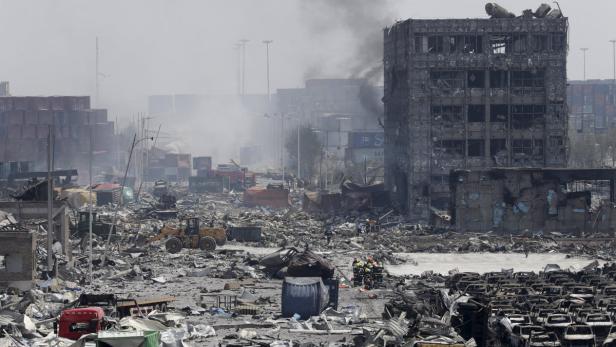 Nach einer Explosion liegen Trümmer und zerstörte Fahrzeuge in einem Industriegebiet.
