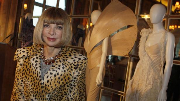 Anna Wintour trägt einen Leopardenmantel neben zwei Mannequins mit Designerkleidung.