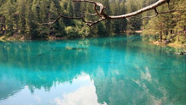 Türkisblaues Wasser spiegelt den Himmel und die umliegenden Bäume wider.