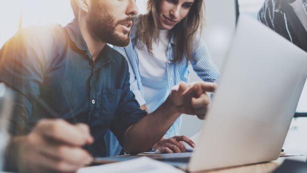 Group of coworkers sitting at the wooden table and working together on new startup project in modern loft office.Horizontal.Blurred background.Cropped. Studie: Potenzial von 85 Milliarden Euro für Österreichs Wirtschaft durch Start-ups