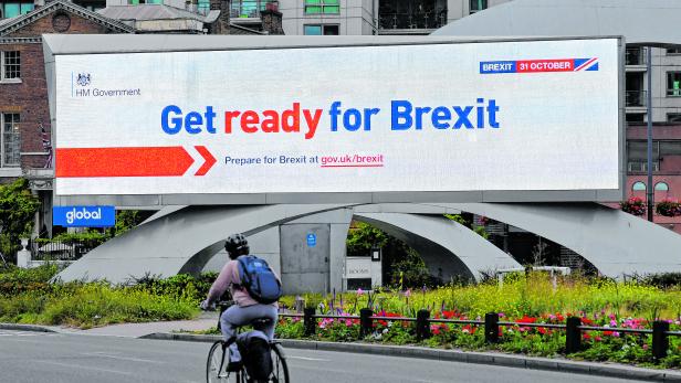 A cyclist rides past an electronic billboard displaying a British government Brexit information awareness campaign advertisement in London, Britain
