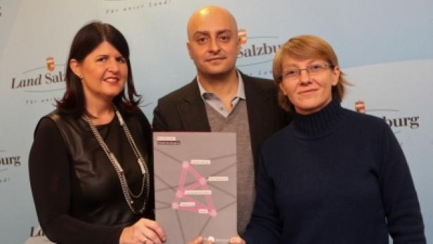 Drei Personen präsentieren eine Grafik vor einem Hintergrund des Landes Salzburg.