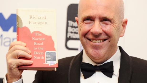 Richard Flanagan hält sein Buch „The Narrow Road to the Deep North“ in die Kamera.