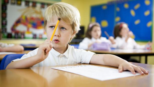 primary school: young boy concentrating over a challenging maths problem