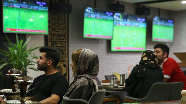 An Iranian woman watch a football match with her friend at a cafe in Tehran
