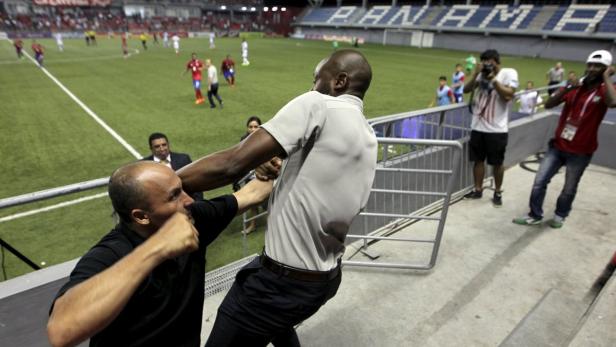 Ein Mann greift einen anderen Mann am Rande eines Fußballfeldes an.