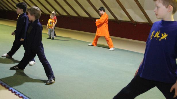 Eine Gruppe von Kindern trainiert Kung Fu in einer Halle.