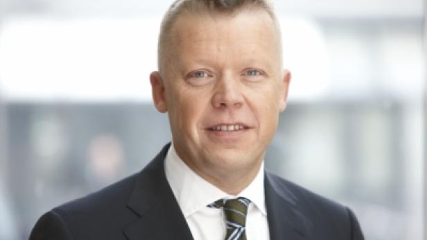 Ein Mann mit Anzug und Krawatte lächelt in die Kamera.