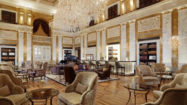 Ein luxuriöser Hotellobby-Bereich mit Sesseln, einer Bar und einem großen Kronleuchter.