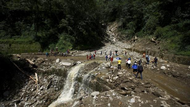 People walk along a blocked highway after a landsl (Symbolbild)