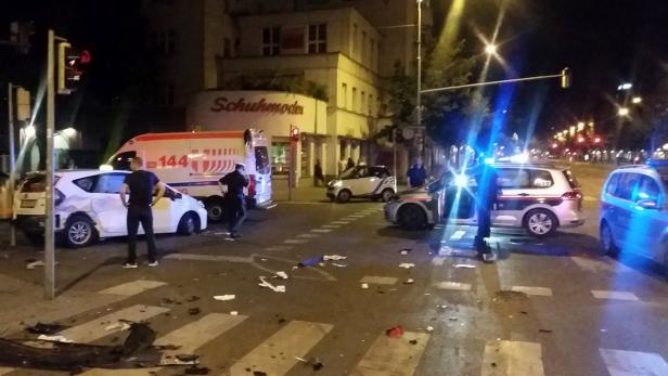 Auf einer Kreuzung stehen mehrere beschädigte Autos, ein Rettungswagen und Polizeiautos mit Blaulicht.