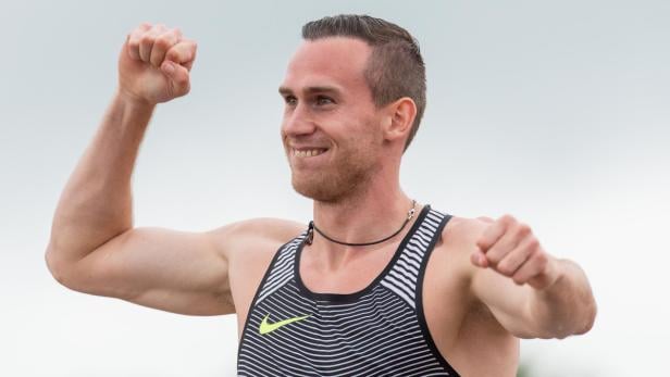 Ein lächelnder Athlet mit erhobenen Fäusten feiert einen Sieg.