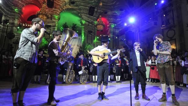 Eine Band spielt in Tracht und mit Blasinstrumenten auf einer Bühne.