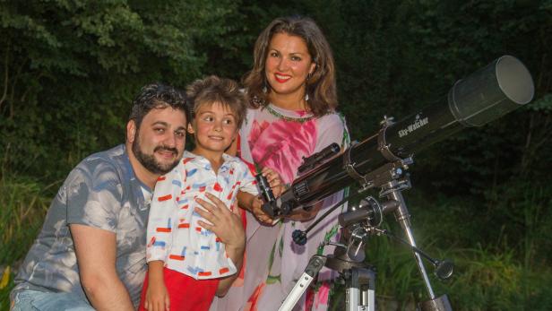 Eine Familie steht mit einem Sky-Watcher Teleskop im Garten.