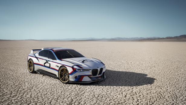 Ein weißer BMW-Rennwagen mit der Nummer 25 steht in einer Wüstenlandschaft.