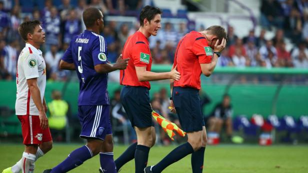 Ein Fußballschiedsrichter hält sich enttäuscht den Kopf, während ein anderer ihn tröstet.