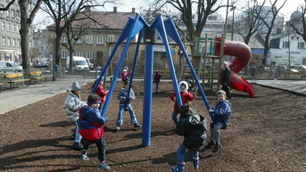 Eine Gruppe Kinder spielt auf einem Karussell auf einem Spielplatz.