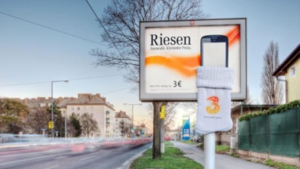 Eine Werbetafel für „Riesen“ mit einem Smartphone, das in eine Socke gesteckt wurde.