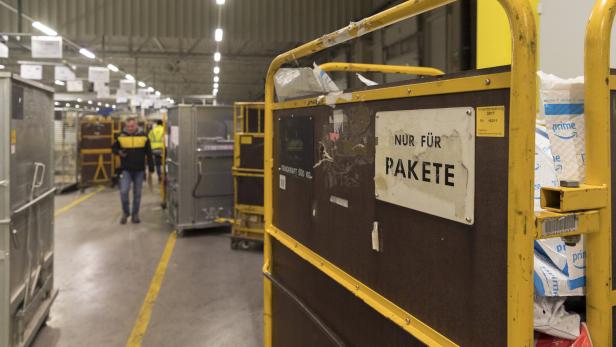 Ein gelber Rollwagen mit der Aufschrift „Nur für Pakete“ in einer Lagerhalle.
