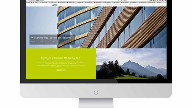 Ein iMac zeigt die Webseite der Moser Holding mit einem modernen Bürogebäude und Berglandschaft.