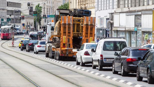 Ein Schwertransporter blockiert die Straßenbahnschienen in einer Stadt.