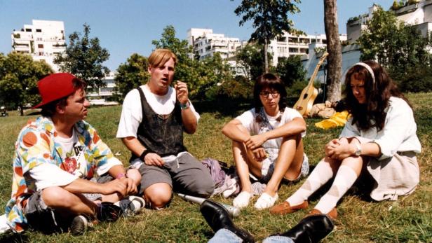 Eine Gruppe junger Leute sitzt im Park auf dem Rasen.