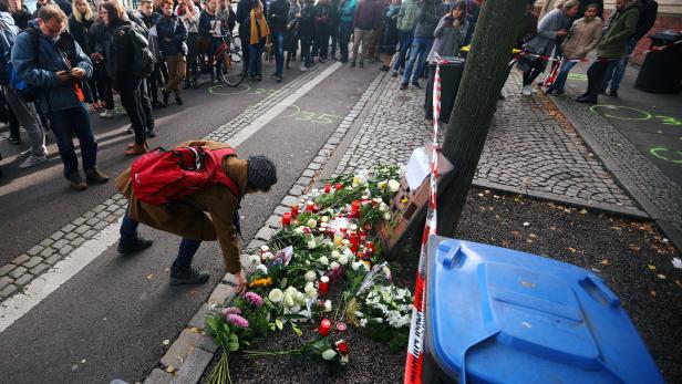 A woman lays flowers as people gather outside a kebab shop in Halle