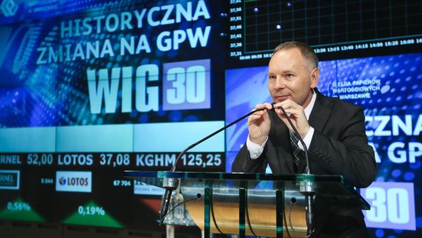 Ein Mann spricht vor einer Anzeigetafel der Warschauer Börse (GPW) mit WIG 30 Index.