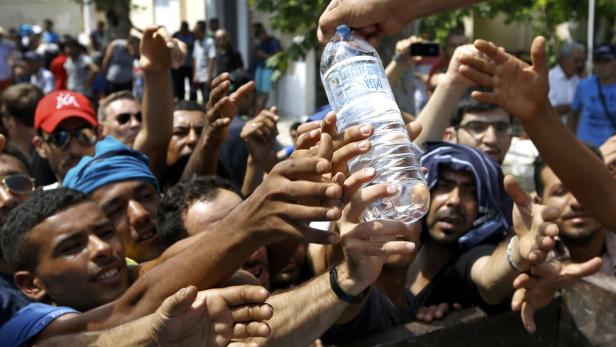 Viele Hände greifen nach einer Wasserflasche.