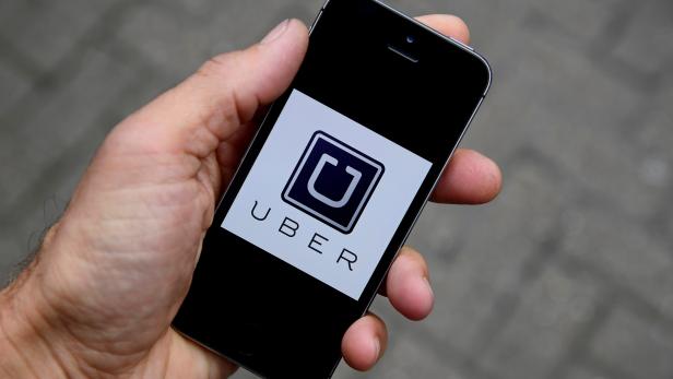 FILE PHOTO: A photo illustration shows the Uber app logo displayed on a mobile telephone, as it is held up for a posed photograph in central London
