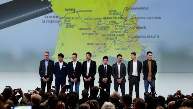 Cyclists pose in front of the map of the 2020 Tour de France cycling race after a news conference in Paris