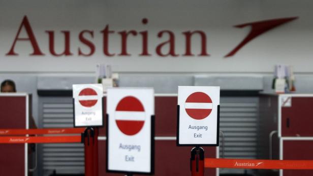 Schilder mit der Aufschrift „Ausgang“ vor einem Austrian Airlines Schalter.