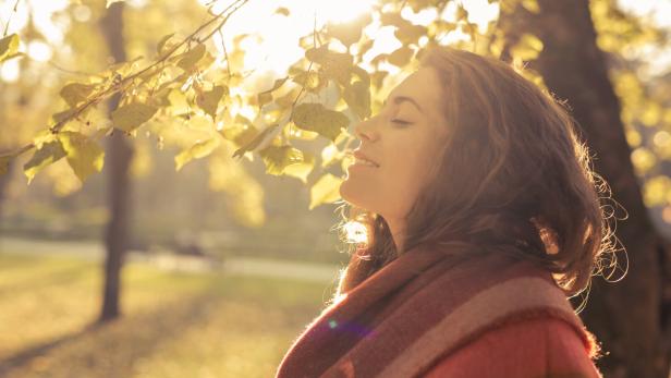 Frau steht in der herbstlichen Abendsonne