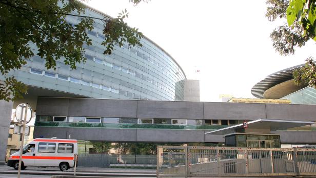 Ein Krankenwagen steht vor einem modernen Gebäude mit Glasfassade.