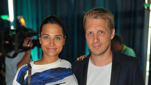Eine Frau in einem blau-weiß gemusterten Kleid posiert mit einem Mann im Blazer für ein Foto.