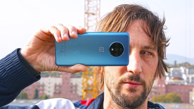 Ein Mann hält ein blaues OnePlus-Smartphone vor sein Gesicht.