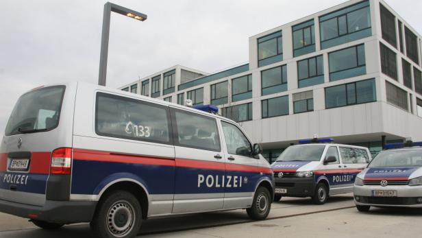 Mehrere Einsatzfahrzeuge der österreichischen Polizei vor einem modernen Gebäude.