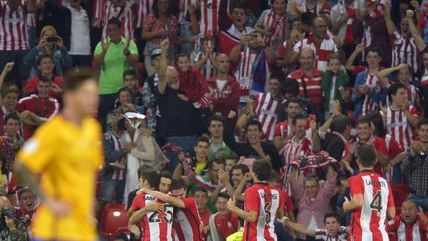 Jubelnde Fußballfans und feiernde Spieler in rot-weiß gestreiften Trikots im Stadion.