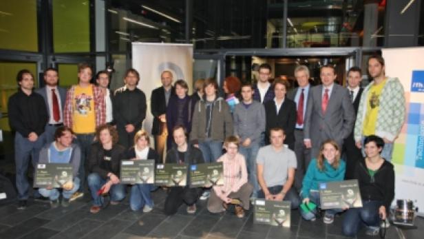 Eine Gruppe von Menschen posiert mit Urkunden für ein Gruppenfoto.