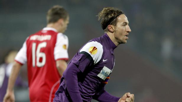 Ein Fußballspieler in lila Trikot mit Stirnband jubelt.