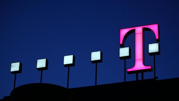 Das beleuchtete T-Mobile-Logo und mehrere kleine, leuchtende Quadrate vor einem dunklen Himmel.