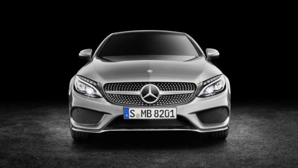 Ein silberner Mercedes-Benz, aufgenommen von vorne vor einem schwarzen Hintergrund.