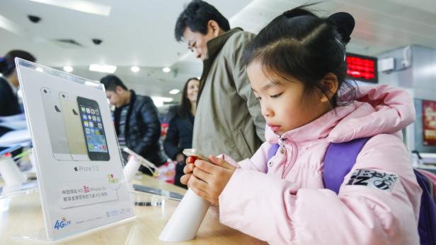 Ein junges Mädchen betrachtet ein iPhone 5s in einem Geschäft.