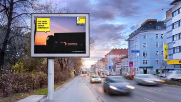 Ein Werbeplakat für LKW Friends mit dem Slogan „Ich habe Ihr Prunkstück gebracht!“ an einer Straße.