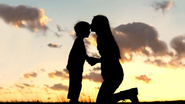 Mother Lovingly Kissing Little Child at Sunset