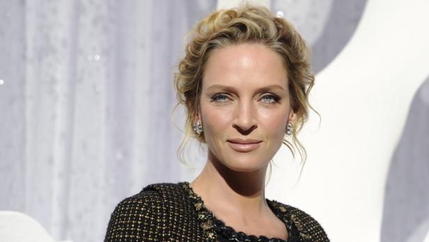 Porträt von Uma Thurman mit blonden Locken und Ohrringen.