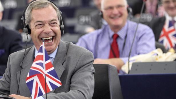 Nigel Farage lacht mit einem Union Jack in der Hand.