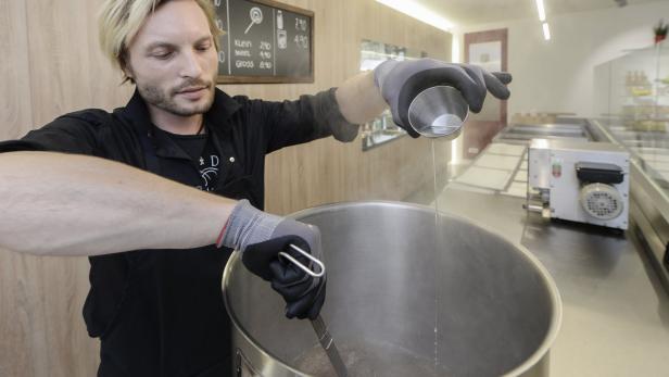 Ein Mann gießt eine Flüssigkeit in einen großen Topf und rührt um.
