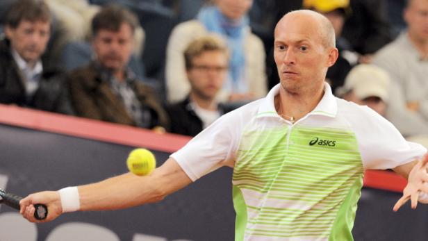 Ein Tennisspieler schlägt einen gelben Tennisball vor Zuschauern.