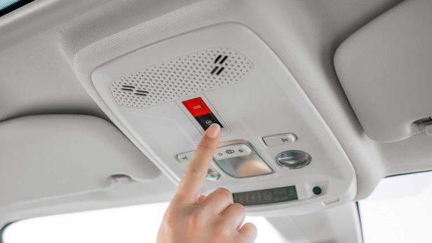 Ein Finger drückt den SOS-Knopf in einem Auto.